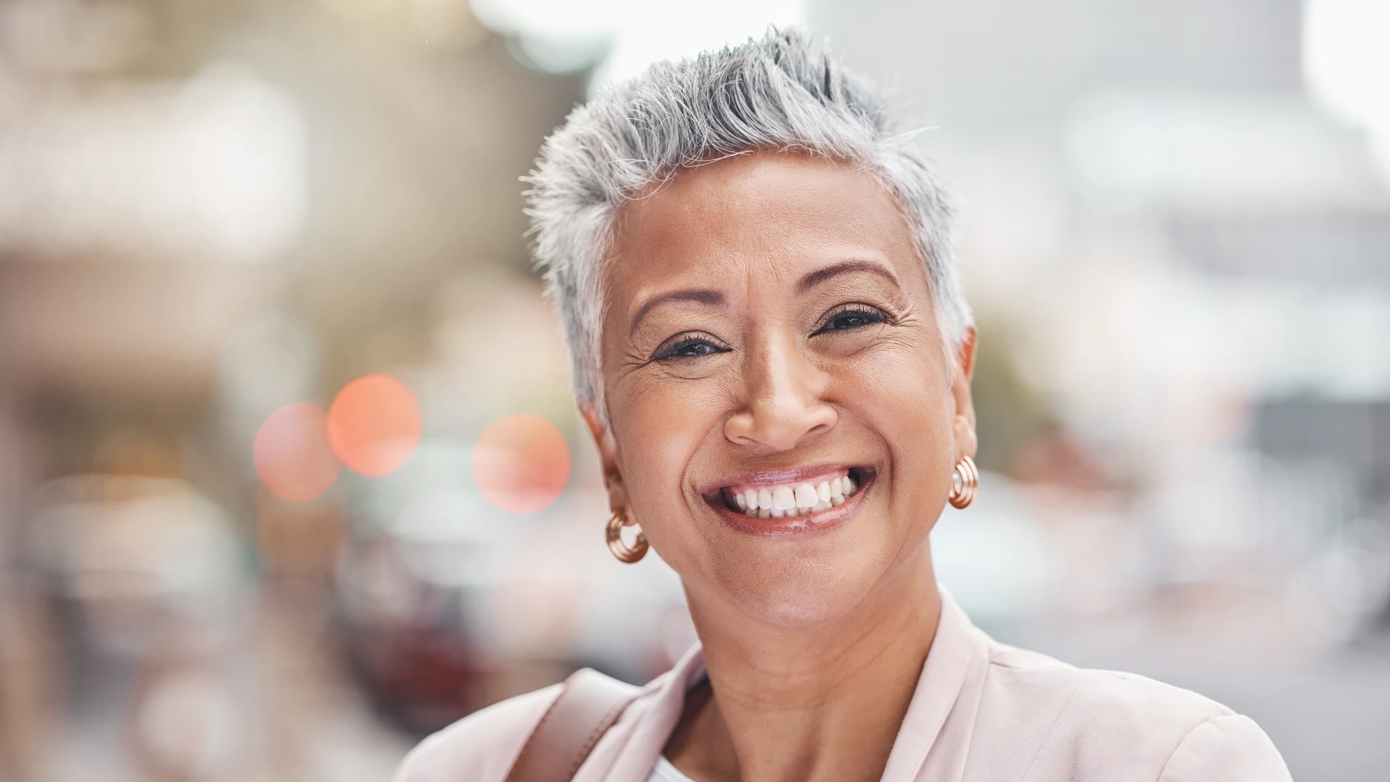 Smiling woman with short grey hair in a pink blouse